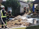 Einsatzkräfte aus Giershagen und Leitmar ziehen unter Atemschutz brennende Strohballen auseinander, um letzte Glutnester abzulöschen.