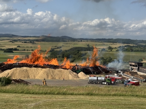 Ein riesiger Holzstapel steht auf dem Gelände eines holzverarbeitenden Betriebs in Somplar lichterloh in Flammen – die Feuerwehr kämpft gegen die Ausbreitung.