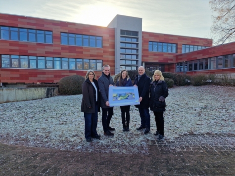 v. l. Projektleiterin Simone Jungermann, Landrat Jürgen van der Horst, Grundschulleiterin Carina Scharlach, Bürgermeister Henning Scheele und Fachdienstleiterin Schulen und Bildung Claudia Knublauch mit dem Konzeptbild des Neubaus am zukünftigen Grundschulstandort vor der MPS Goddelsheim. Foto: Landkreis Waldeck-Frankenberg