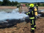 Einsatzkräfte der Feuerwehren Meineringhausen und Strothe bekämpfen unter Atemschutz die Flammen auf dem Stoppelfeld.